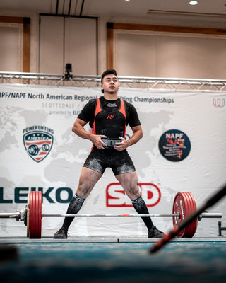 Powerlifter preparing to deadlift on a competition platform.